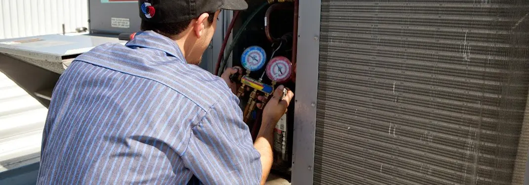 HVAC technician servicing a condenser unit in Pomfret